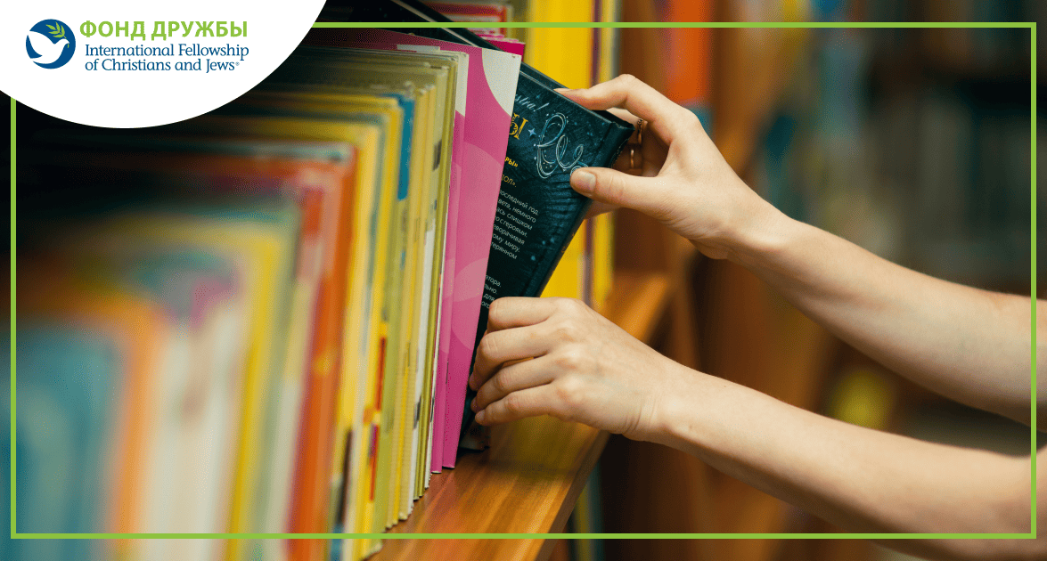 Руки человека выбирают книгу с полки в библиотеке или книжном магазине.