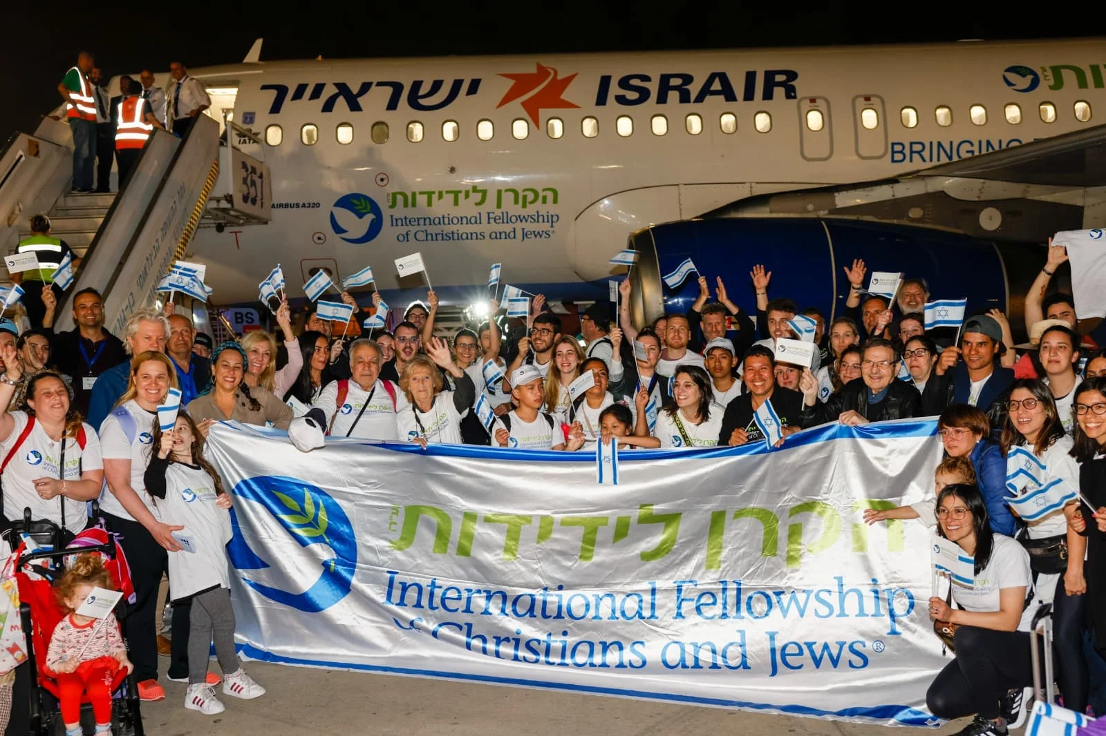 Группа новых репатриантов с флагами Израиля у самолёта Israir, прилетевших в Израиль при поддержке Международного фонда дружбы христиан и евреев.