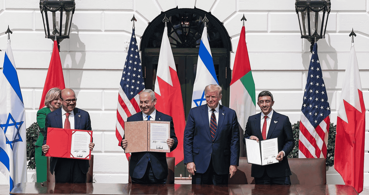 Лидеры Израиля, США, Бахрейна и Объединённых Арабских Эмиратов стоят перед флагами своих стран и держат подписанные документы во время церемонии подписания соглашений в Белом доме.